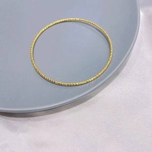 Close-up of sparkling diamond-cut texture on a slim 18K gold-plated titanium bangle