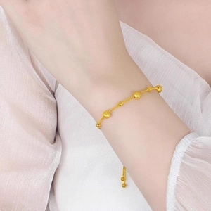18K gold plated titanium beaded adjustable pull-string bracelet worn on a woman's wrist