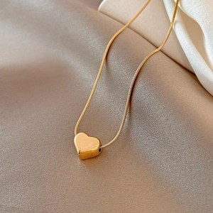 Elegant gold titanium steel heart pendant necklace on a champagne silk background