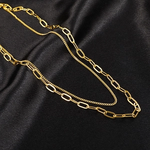 Double-layered gold paperclip and link chain necklace set on black luxury satin