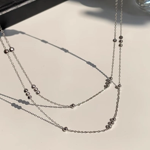 Double-layered stainless steel bead necklace with a minimalist polished finish on white