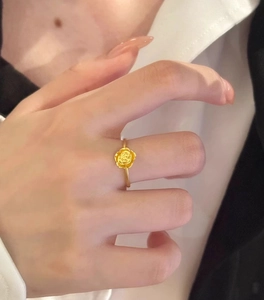 Detail of a 3D gold rose flower ring on finger showing petals and thin circular band