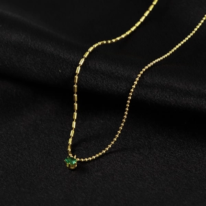 Collier minimaliste en titane doré avec pendentif gemme verte sur satin noir