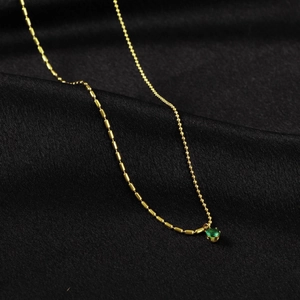 Collier minimaliste en perles dorées avec pendentif émeraude sur soie noire