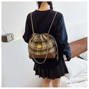 Detail view of plaid wool bucket bag with gold chain strap and drawstring closure