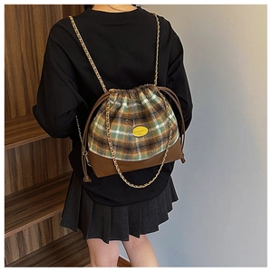Detail of green and yellow plaid wool backpack with leather base and gold chain strap