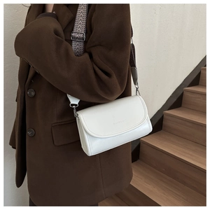 Close-up of white leather crossbody bag with jacquard wide strap on a model