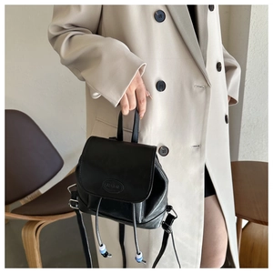 Detail of black PU leather mini backpack with drawstring and blue beaded accents