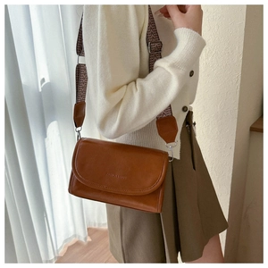 Detail of caramel brown crossbody bag with ethnic style wide fabric shoulder strap