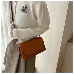Detail of vintage brown leather crossbody bag with fashion stamp and woven strap