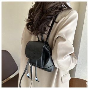 Close-up of minimalist black PU leather backpack with drawstring and bead details