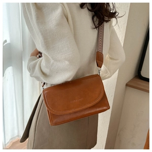 Detail view of caramel brown crossbody bag featuring ethnic style woven wide shoulder strap