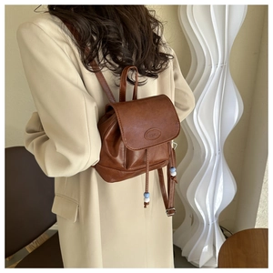 Close-up of vintage brown PU mini backpack with fashion logo and bead drawstring details