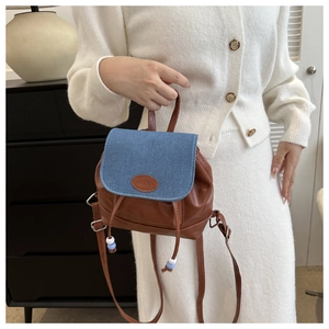 Detail of mini backpack featuring brown faux leather and blue denim patchwork design