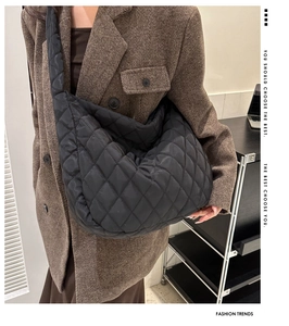 Detail of black quilted crossbody bag showing glossy rhombus pattern and wide shoulder strap