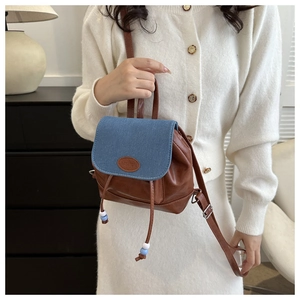 Detail of a mini leather backpack with denim flap, drawstring closure and fashion patch