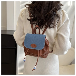 Detail of mini bucket backpack with blue denim flap and brown leather drawstring closure