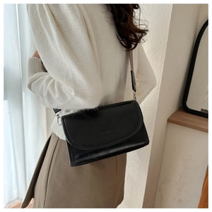Detail of black PU leather crossbody bag featuring wide woven strap and embossed text