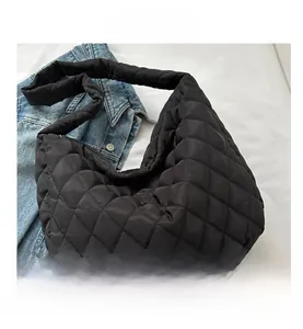 Close-up of black quilted shoulder bag with rhombus stitching and smooth zipper closure