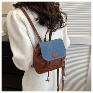 Detail of mini vintage backpack with brown PU leather and blue denim flap on a model