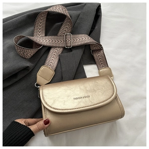 Detail of champagne gold leather bag with textured finish and geometric patterned strap