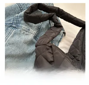 Detail of black quilted cloud bag with diamond stitching shown with denim jacket