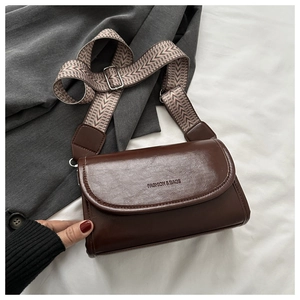 Detail of deep brown square crossbody bag featuring wide herringbone pattern strap