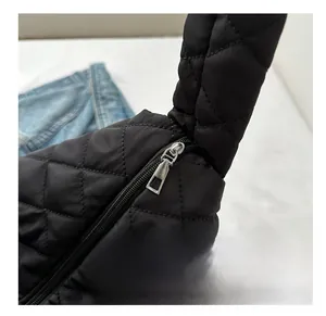 Detail shot of smooth silver metal zipper on black quilted nylon tote bag with stitching