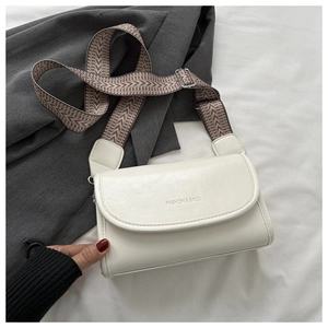 Detail view of a white leather crossbody bag with a decorative geometric wide shoulder strap