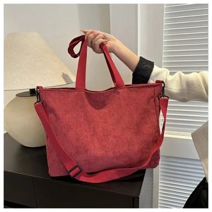 Detail of red corduroy tote bag showing vertical texture and adjustable shoulder strap