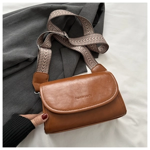 Detail of brown leather crossbody bag with geometric woven strap and embossed text