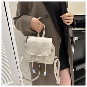 Detail of beige PU leather backpack featuring drawstring closure and blue accent beads