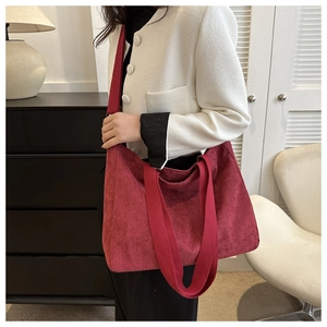 Detail of burgundy corduroy tote bag showing the vertical texture and wide shoulder strap