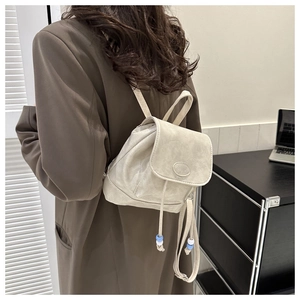Detailed view of cream mini PU backpack with drawstring closure and bead accents