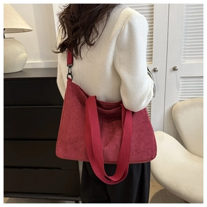 Detail of red corduroy tote bag featuring thick texture and black metal hardware