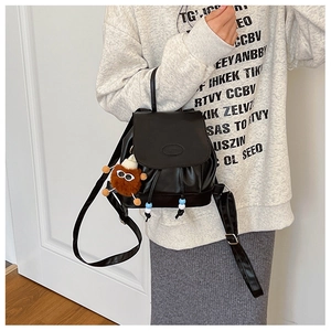 Detail of a black PU mini backpack with plush bear charm and decorative beaded drawstring