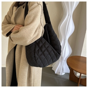 Detail of black quilted hobo bag with classic diamond stitching and wide shoulder strap