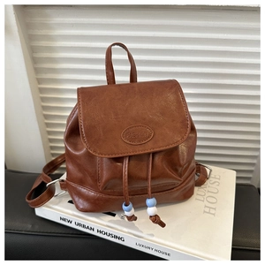 Detail of a brown faux leather mini backpack with drawstring closure and bead accents