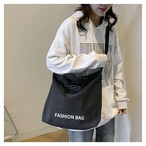 Trageansicht der großen schwarzen Canvas-Tragetasche mit FASHION BAG Aufdruck