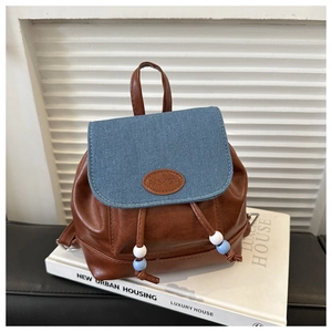 Detail of mini backpack featuring contrast denim flap, drawstring with beads and top handle
