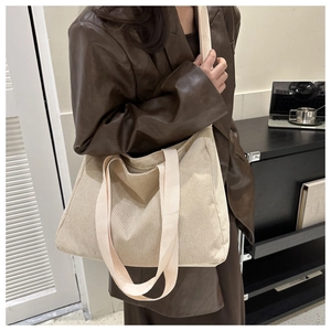 Detail of beige corduroy tote bag featuring vertical ribbed texture and wide shoulder strap