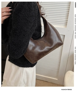 Detail of dark brown retro crescent underarm bag with embossed fashion text and rivets
