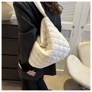 Close-up of white quilted nylon tote bag with soft puffer texture and diamond patterns