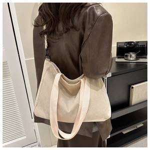 Detail of off-white corduroy tote bag showing wide straps and black metal hardware