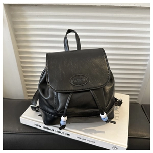 Close-up of black PU leather mini backpack featuring flap drawstring and blue bead charms