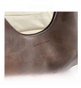 Close-up of brown vintage leather bag showing zipper and FASHION & BAGS embossed logo