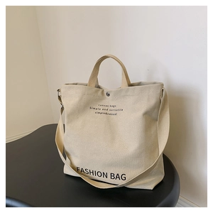 Nahaufnahme der cremefarbenen Canvas-Tasche mit schwarzem Aufdruck und Trageriemen