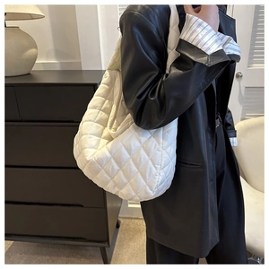 Macro detail of white quilted nylon tote bag showing soft puff texture and diamond stitching