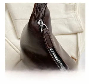 Detail shot of smooth silver zipper and leather puller on dark brown shoulder bag