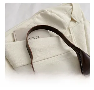 Detail of soft padded handle and premium leather texture on dark brown underarm bag